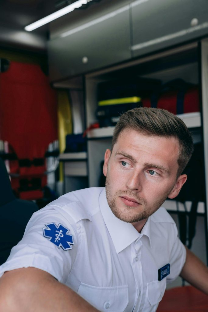 Portrait of a paramedic sitting inside an ambulance, showcasing EMS uniform and equipment.