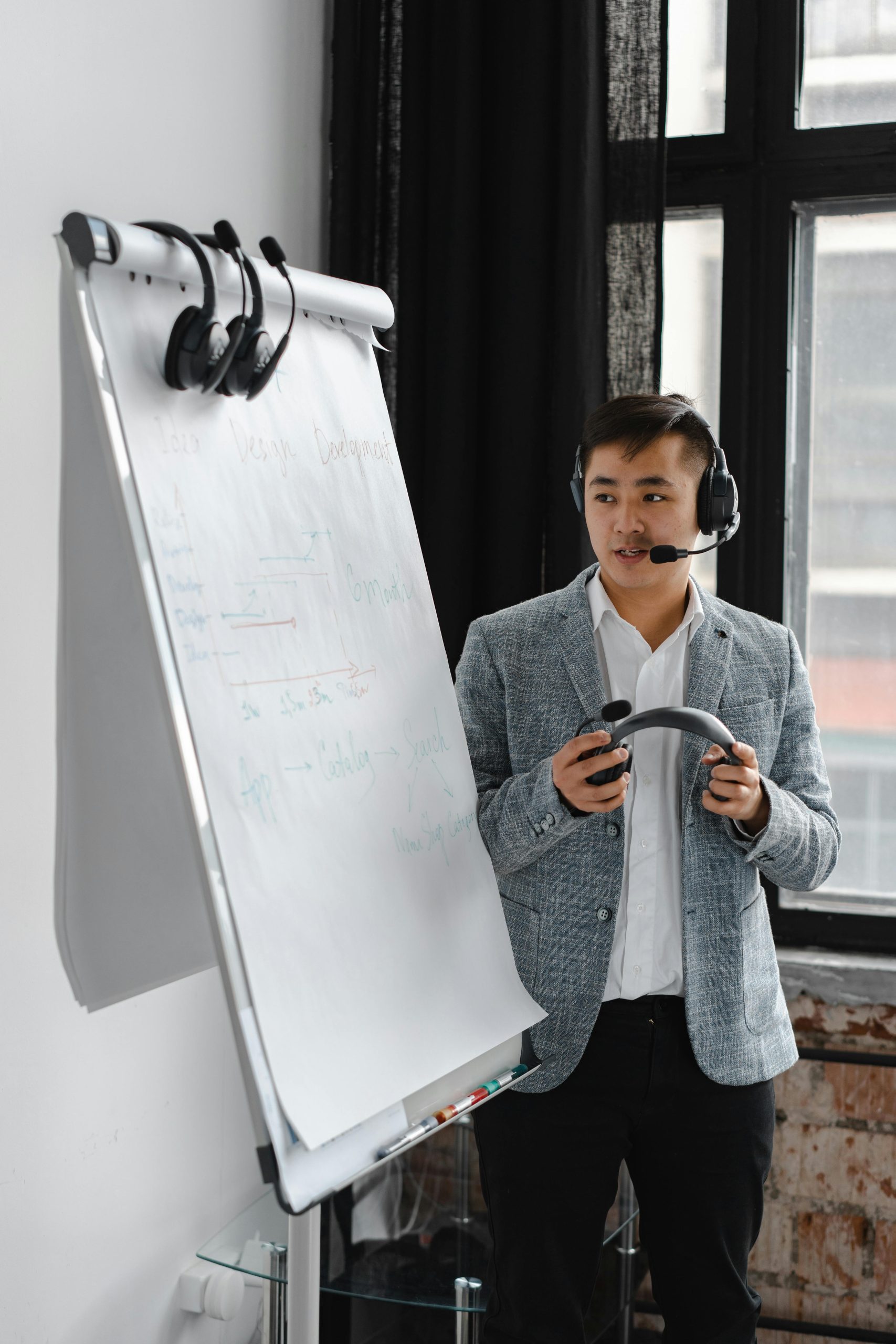 Asian man with headset explains on a flipchart during a virtual meeting. Ideal for business and communication themes.