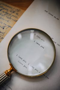 Close-up of a magnifying glass highlighting 'I love you' on a letter, capturing romantic sentiment.